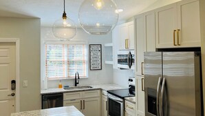 A modern kitchen with granite countertops, stainless steel appliances, and pendant lighting.