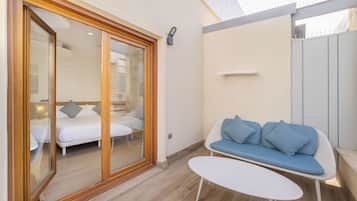 Quarto moderno com porta de correr de vidro que dá para um quarto, um sofá branco com almofadas azuis e uma pequena mesa branca.