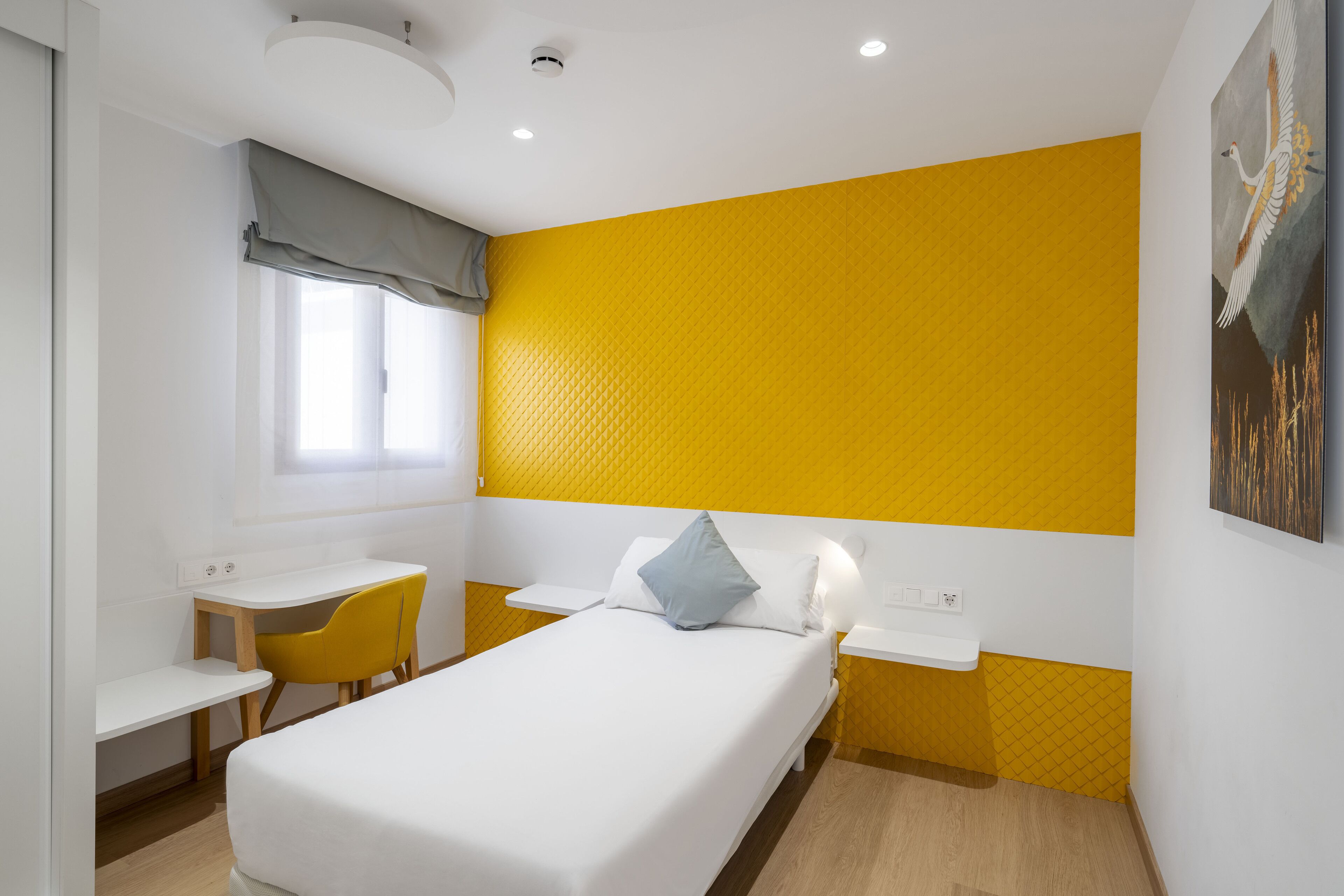 A compact hotel room with a bed, a desk, and a chair.