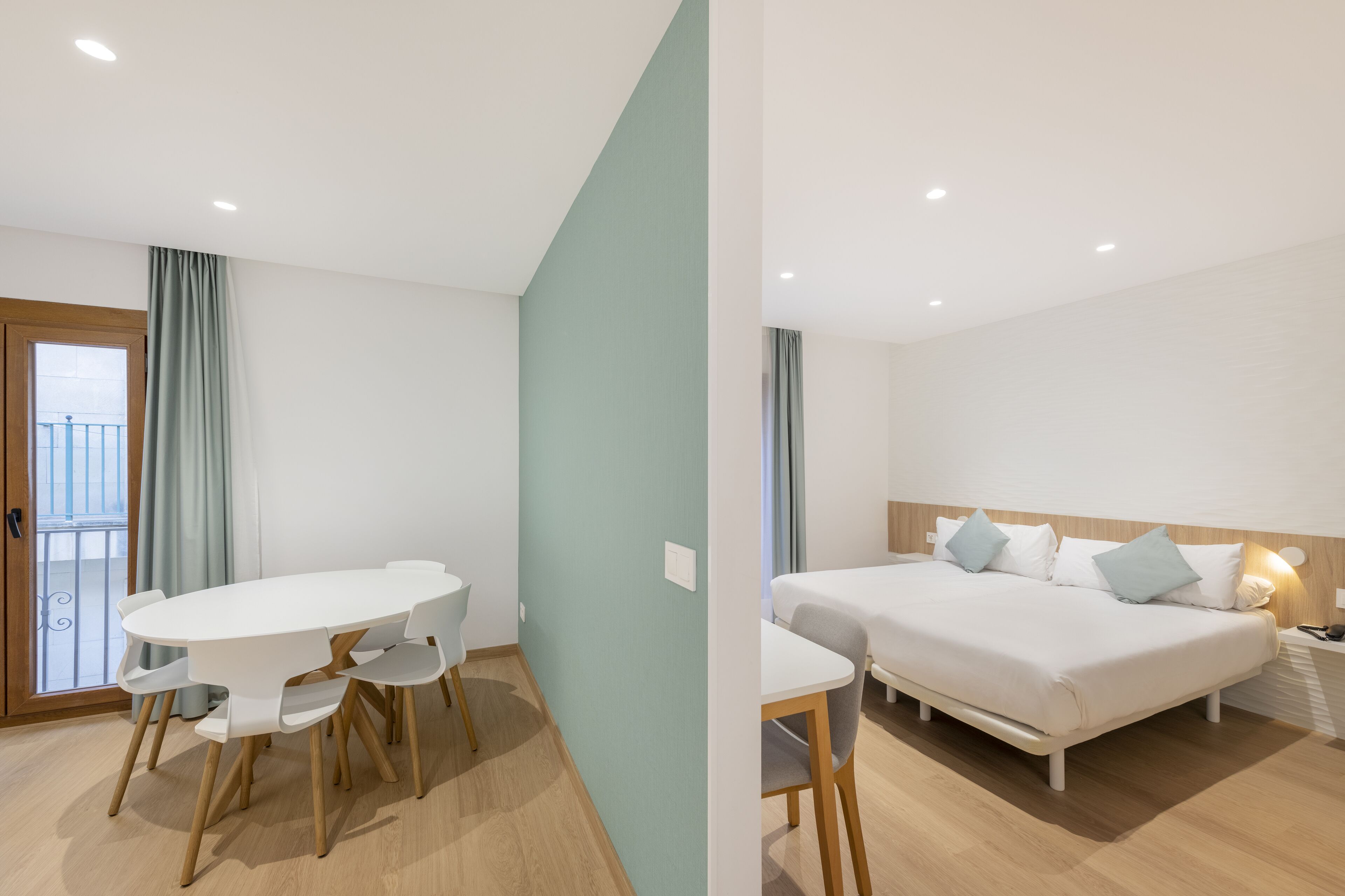 Una habitación de hotel moderna con zona de comedor, cama y balcón.