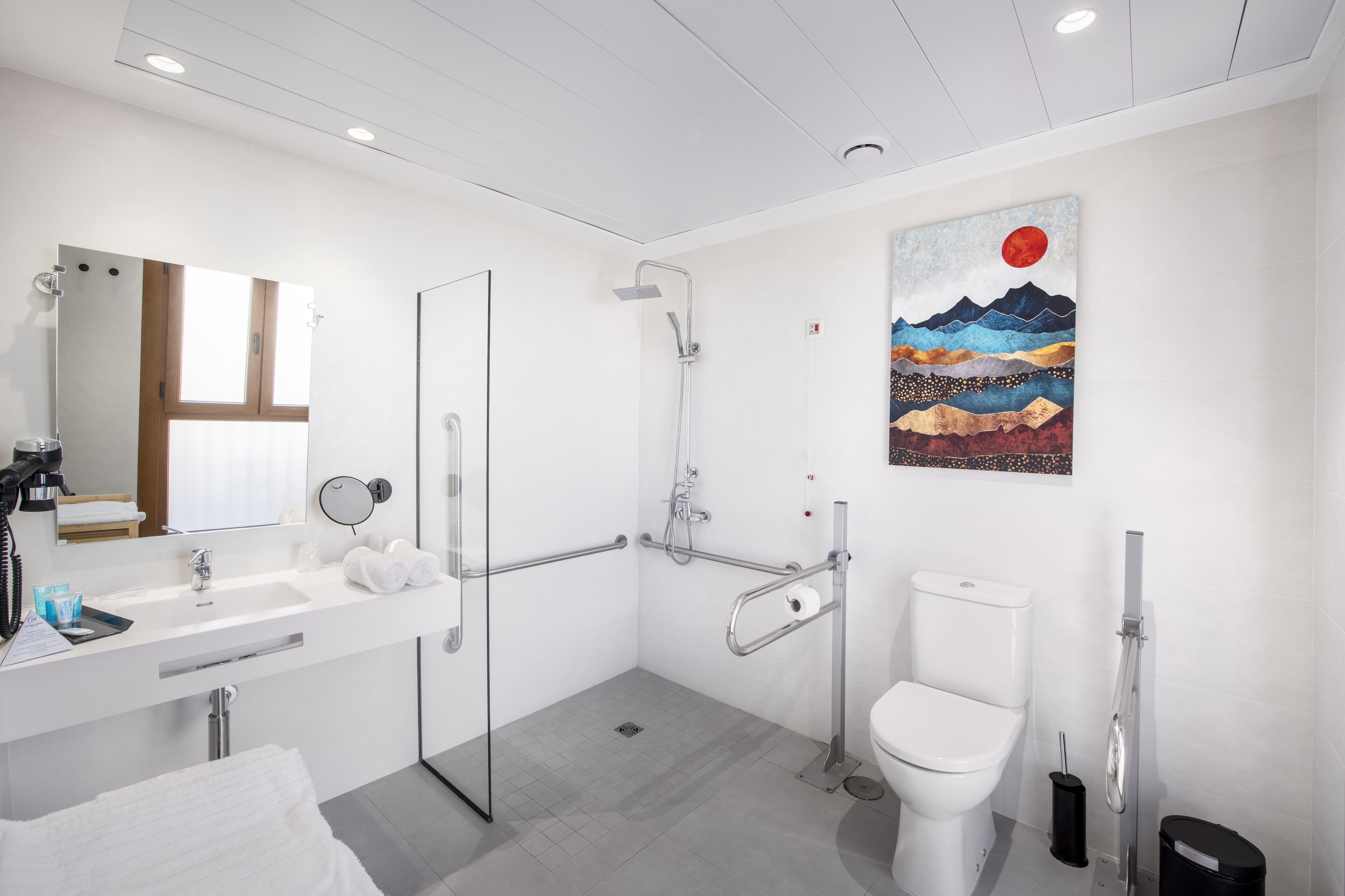 A modern bathroom with a glass shower enclosure, a white sink with a mirror, and a toilet.