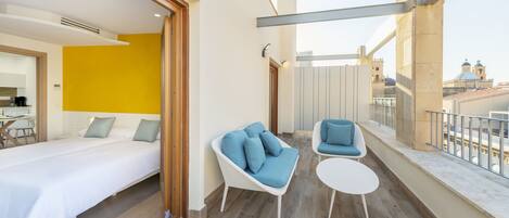 Een moderne hotelkamer met een bed, een bank en een balkon met uitzicht op de stad.