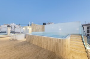 A rooftop pool area with wooden flooring, a glass railing, and a modern design.