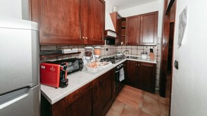 Una cocina con gabinetes de madera, microondas, cocina a gas y cafetera.