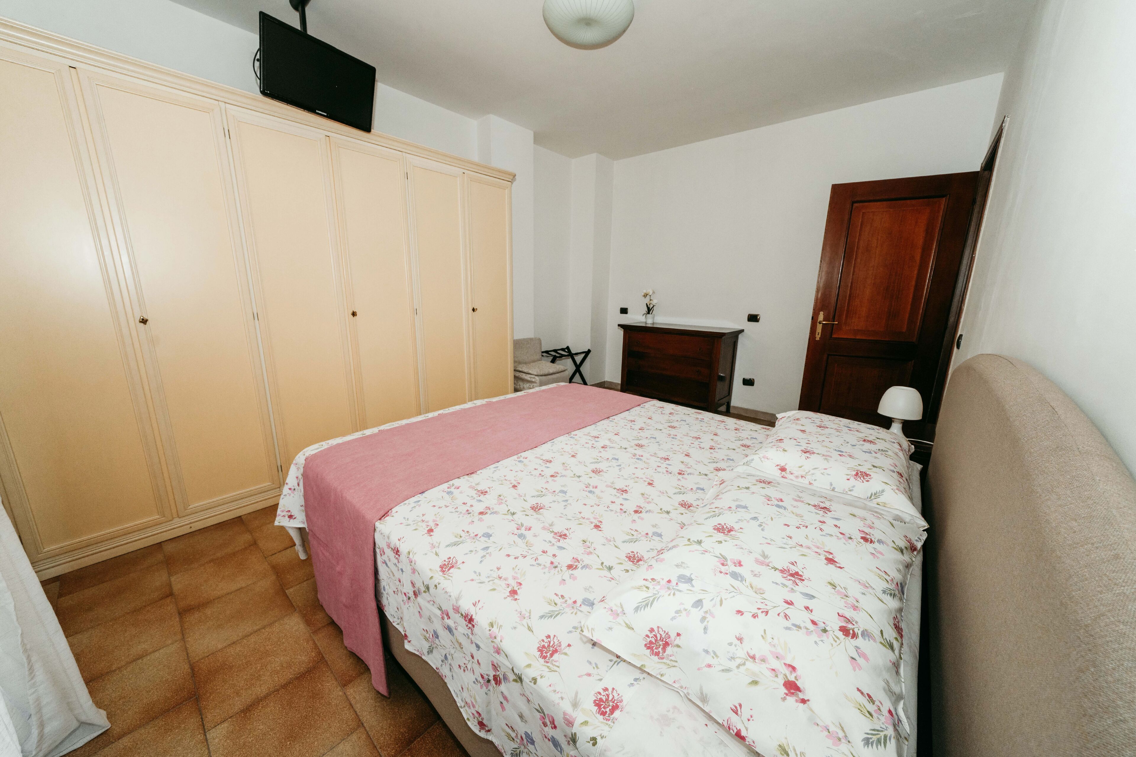 A bedroom with a bed, a wardrobe, a desk, and a chair.