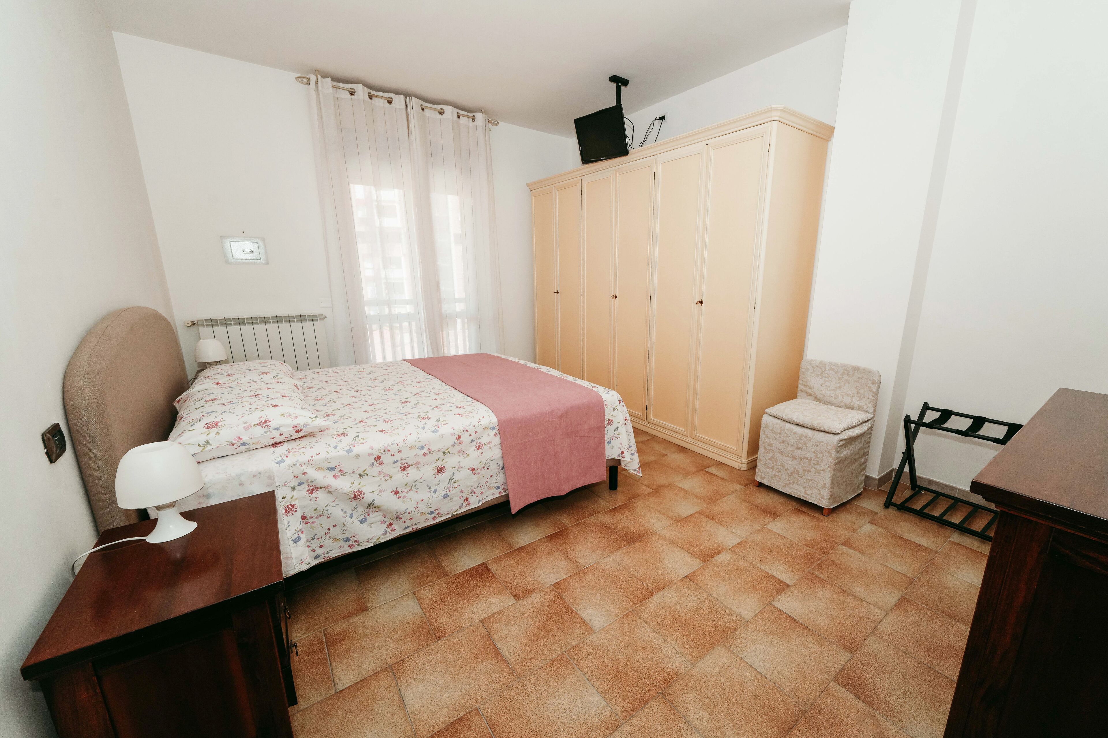 A bedroom with a bed, a wardrobe, a chair, and a desk.