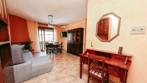 Una sala de estar con un sofá, un escritorio de madera y un televisor.