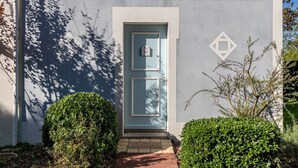 Ein Gebäude mit einer hellblauen Tür, einer Nummertafel und einem geometrischen Symbol an der Wand.