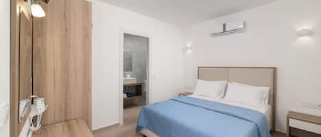 A modern bedroom with a large bed, bedside tables, a wooden bench, a mirror, and an air conditioning unit.