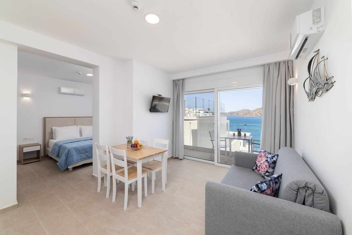 Una habitación de hotel moderna con balcón, comedor y sofá.
