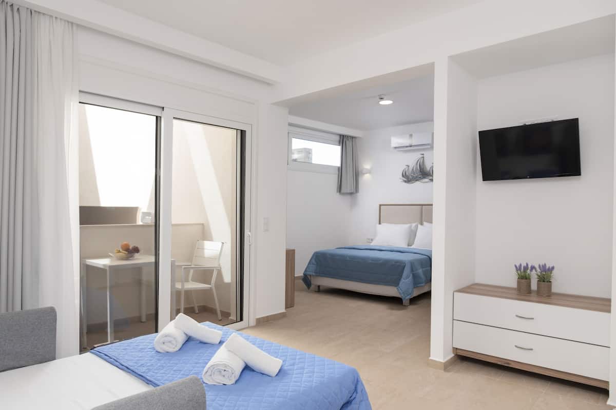 Habitación de hotel moderna con cama, escritorio, silla, televisor y puerta corredera que da a un balcón.
