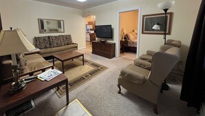 A living room with a sofa, coffee table, TV, and a dining area with chairs and a table. - Harlan, KY Modern Private Guesthouse 302 Historic Downtown (Vela's Villas) (Harlan)