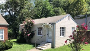 A small, single-story house with a brick exterior, a white door, and a small porch with steps leading up to it. - Harlan, KY Modern Private Guesthouse 302 Historic Downtown (Vela's Villas) (Harlan)