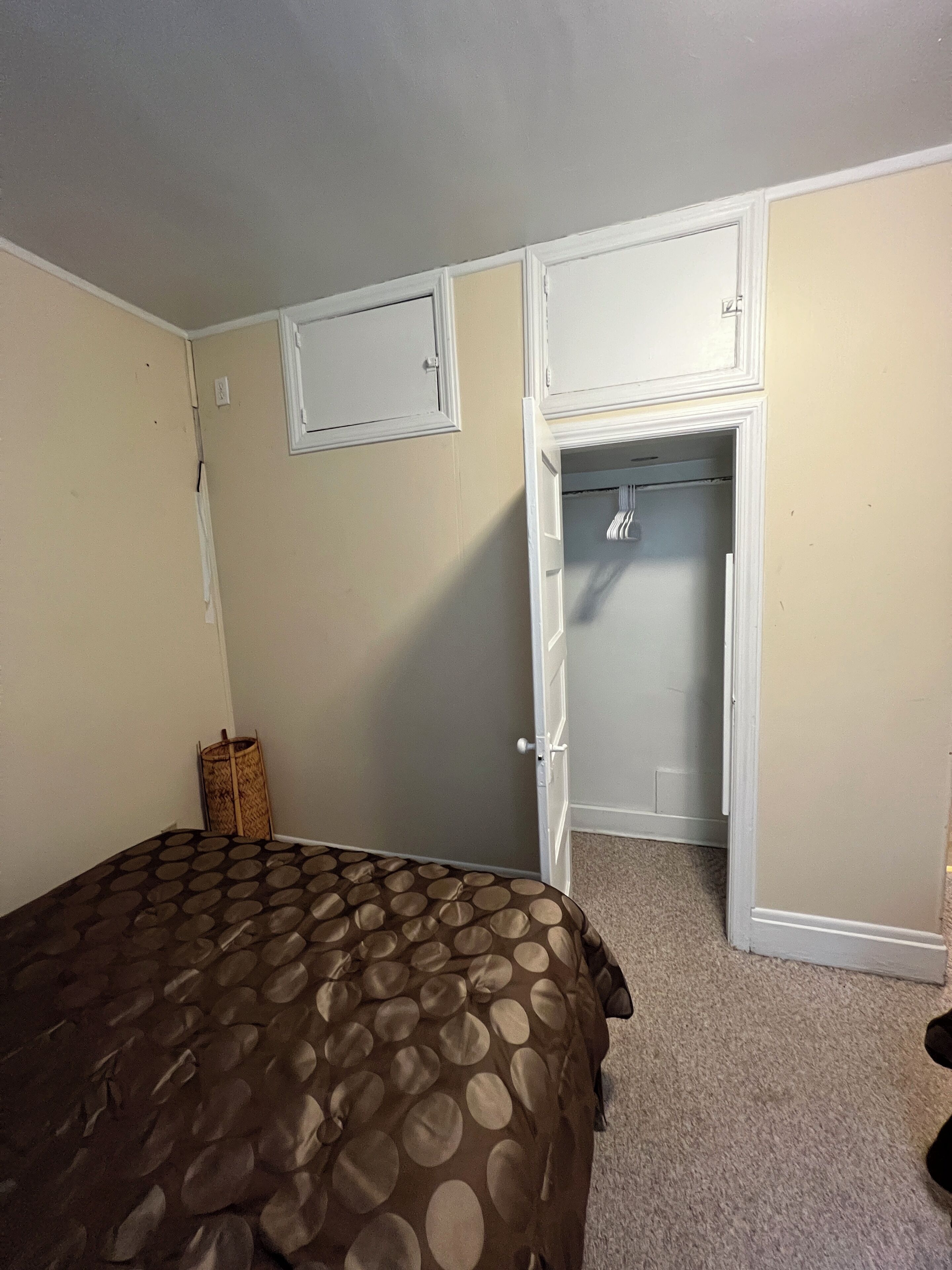 A bedroom with a bed, a closet, and a door leading to another room.