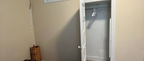 A bedroom with a bed, a closet, and a door leading to another room.