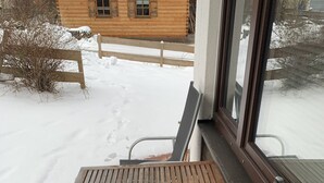 Ett träbord och två stolar på en uteplats med ett snötäckt underlag.
