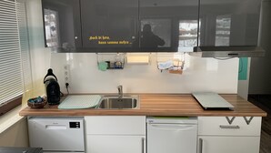 Ett modernt kök med en diskho i rostfritt stål, en kaffemaskin och en diskmaskin.