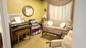 Un salon comprenant un piano, un canapé, une table basse et un tapis à motifs.