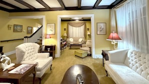 Un vaste salon doté d’un haut plafond, d’un escalier et d’un coin salon confortable avec un canapé et des fauteuils.