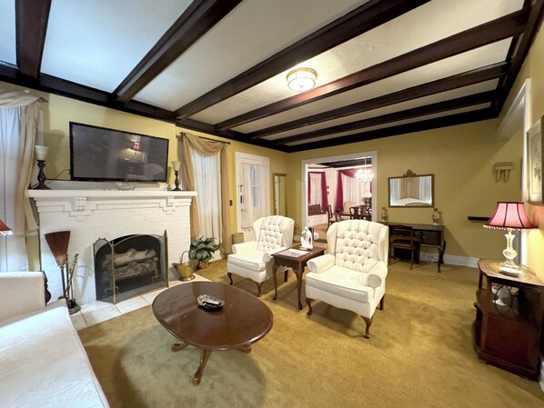 A living room with a fireplace, two armchairs, a coffee table, and a television.