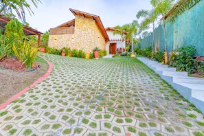 Un chemin pavé mène à un bâtiment doté d’une façade en pierre et d’un toit en bois.