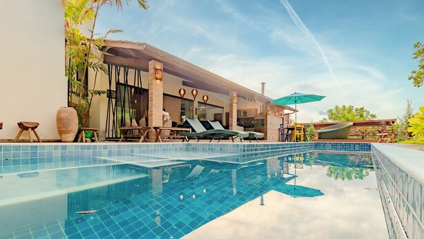 Ein Swimmingpool mit Liegestühlen und einer überdachten Sitzgruppe.
