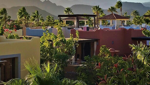 A resort with a pool area, covered seating, and palm trees.