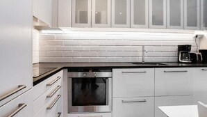 Een moderne keuken met witte kasten, een roestvrijstalen oven en een zwart aanrecht.