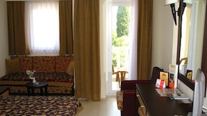 A hotel room with a bed, a sofa, a desk with a computer, and a view of the outdoors.