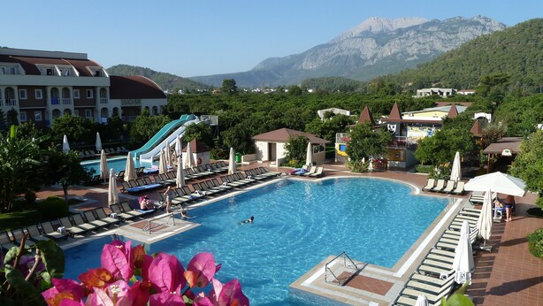 A swimming pool with a slide, lounge chairs, and a snack bar.