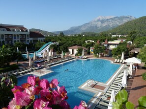 A swimming pool with a slide, lounge chairs, and a snack bar. - Viking Garden Hotel - All inclusive (Kemer)