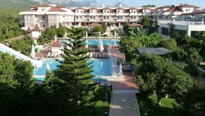 A resort with multiple swimming pools, a central courtyard, and a mountain backdrop.