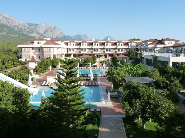 Ein Resort mit mehreren Swimmingpools, einem zentralen Innenhof und einer Bergkulisse.