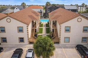 A multi-story building with a central courtyard, a swimming pool, and a parking lot.