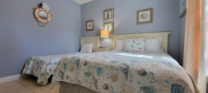 Un dormitorio con cama, mesita de noche, lámpara y adornos en la pared.