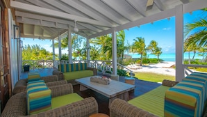 Un espace extérieur aménagé, abrité et doté de mobilier en osier, offrant une vue sur la plage.