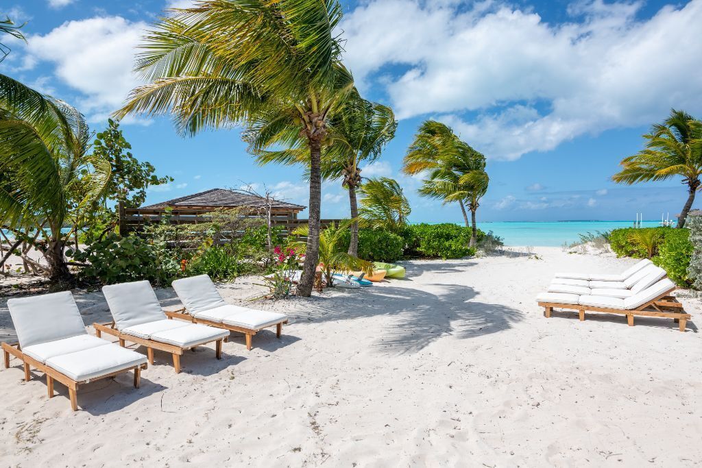 Une plage avec des chaises longues en bois et une petite cabane en arrière-plan.