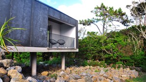A modern house with a balcony, surrounded by rocks and greenery. - Casas do Morgadio - azorean wine & lodge (Praia da Vitoria)
