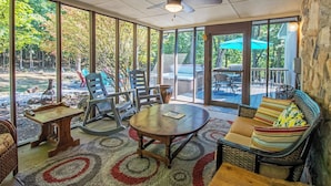 A sunroom with a large glass door, a ceiling fan, a round wooden table, and wicker furniture. - Private Hot Tub and Resort Amenities Included! (Massanutten)
