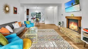 A modern living room with a fireplace, a sofa, a coffee table, and a TV. - Groovy Getaway | Lake Access, Pool, Tennis, 72-Hr Boat Parking (Canyon Lake)