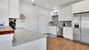 A modern kitchen with white cabinets, a stainless steel refrigerator, and a granite countertop. - Come stay at the Oasis by the Lake! (Canyon Lake)
