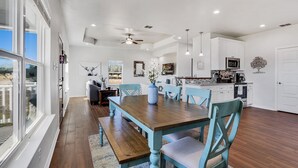 A spacious kitchen with white cabinets, a dining table, and a ceiling fan. - Come stay at the Oasis by the Lake! (Canyon Lake)