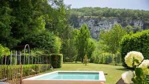 A swimming pool with a view of a natural landscape and a cliff.