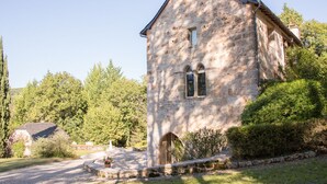 A stone building with a pitched roof, arched windows, and a small door.