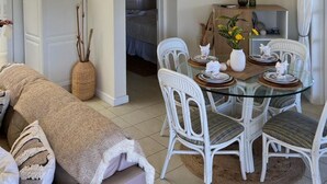 Amplia sala de estar con techos altos, una mesa de comedor rodeada de sillas blancas y un rincón de estar acogedor con un sofá.