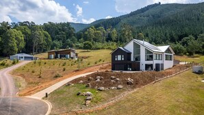 Ein modernes, zweistöckiges Haus mit großem Vorgarten, einer Auffahrt und einem Berg im Hintergrund.