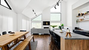 Eine moderne Küche mit einem Holztisch, einer integrierten Bank sowie einer Bar mit Hockern.