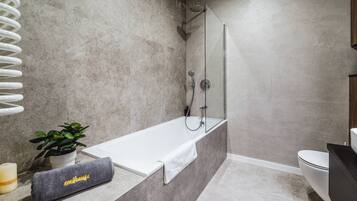 A modern bathroom with a freestanding bathtub, a shower, and a toilet.