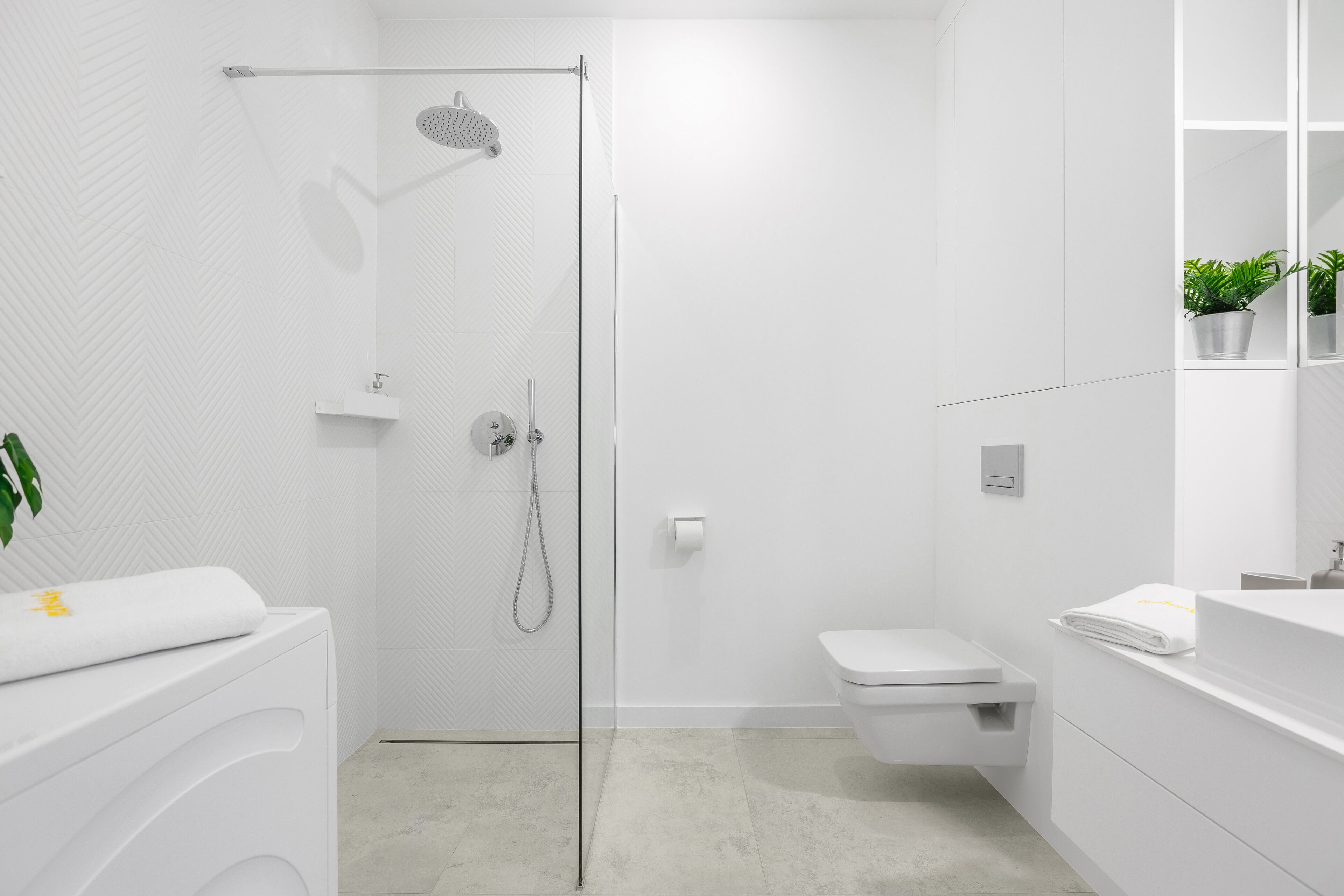 A modern bathroom with a shower, toilet, and sink.