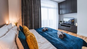 Een moderne slaapkamer met een groot bed, een televisie en donkere kasten.